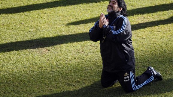 Argentina s soccer team coach Diego Maradona kneels while speaking to a journalist 