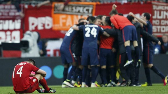 Bayern s Xabi Alonso sits on the pitch as Atletico players celebrate 