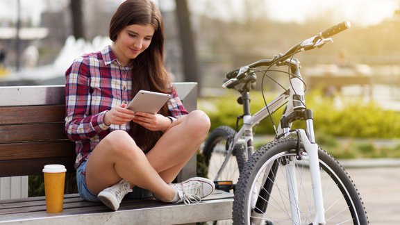 velosipēdiste studente parks soliņš planšete lasīt