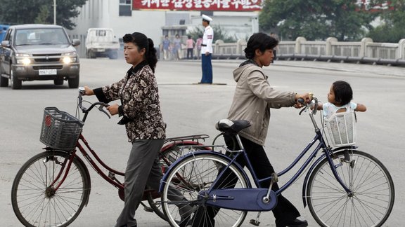 North Korean women push bicycles 