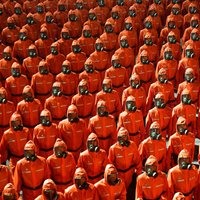 Ziemeļkorejas dibināšanas gadadienas parādē maršē cilvēki aizsargtērpos
