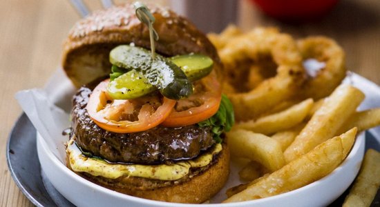 Sulīgs liellopa gaļas burgers ar ceptiem sīpolu gredzeniem mājas gaumē