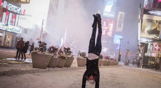 Dienas ceļojumu foto: Tūrists pozē, stāvot uz rokām, sniega vētras laikā Ņujorkā