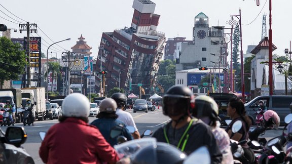 Local residents ride past a damage of building caused by the earthquake in Hualien on April 4, 2024. At least nine people were killed and more than 1,000 injured by a powerful earthquake in Taiwan that damaged dozens of buildings and prompted tsunami warnings as far as Japan and the Philippines before being lifted. 