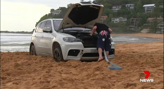 Video: Sidnejā pludmalē iestieg 'BMW X5', tikai traktors spēj palīdzēt