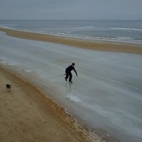 Drona video: Suņuks Mesiņš izved pastaigā saimnieku, kurš slido pa aizsalušu jūru