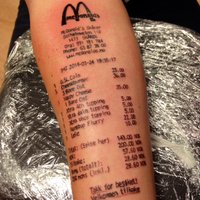 Pusaudzis uz rokas uztetovē 'McDonald's' čeku