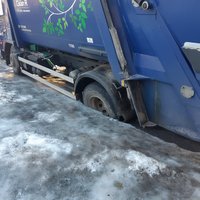 Foto: Atkritumu vedējs Rīgā iestieg lielā bedrē