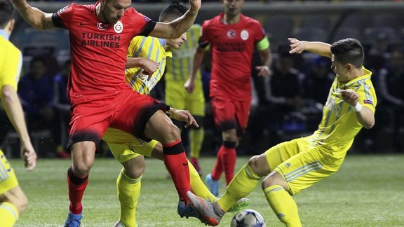 Galatasaray s Lukas Podolski, left, vies for a ball with Astana s Georgi Zhukov