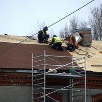 Foto: Strādnieki 'drošsirdīgi' liek jumta segumu