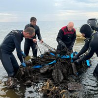 Foto un video: No Rīgas jūras līča izvelk trīstonnīgu vecu zvejas tīklu murskuli