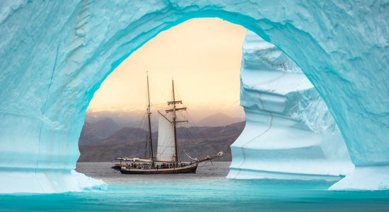 Dienas ceļojumu foto: Laiviņa dreifē cauri milzīgam aisbergam