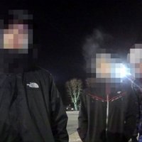 Trīs poļu jaunieši pie Brīvības pieminekļa pozē ar nolaistām biksēm