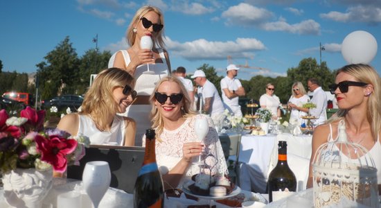 Foto: Baltā tērpti ļaudis pikniko topošajā "Riga Waterfront"