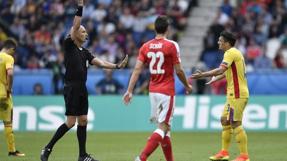 Referee Sergei Karasev shows a yellow card to Romania s Claudiu Keseru,